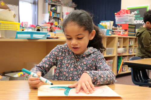 A student colors at her desk